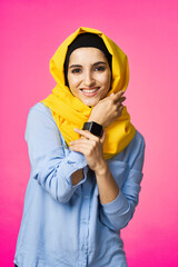 cheerful woman in yellow hijab electronic watch technology user pink background