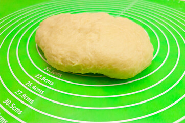 Piece of finished dough on green silicone mat, top view