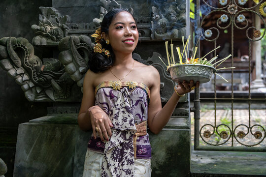 Balinese girl in a Hindu temple in Bali with incense sticks dressed in traditional dress. 