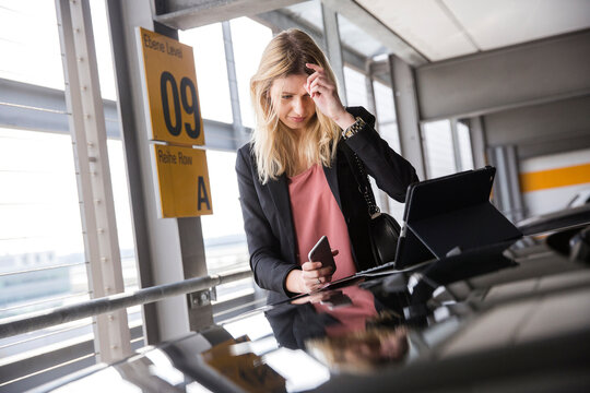 Young woman looking at digital tablet in parking lot