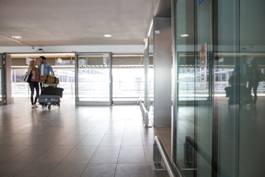 Young Couple With Luggage Trolley At Airport Terminal