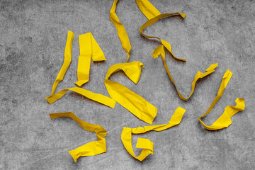 scraps of yellow crumpled paper on a gray shabby background; problems of recycling and reuse of paper