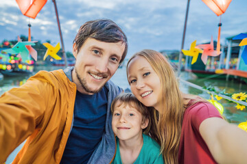 Happy family of travelers ride a national boat on background of Hoi An ancient town, Vietnam. Vietnam opens to tourists again after quarantine Coronovirus COVID 19