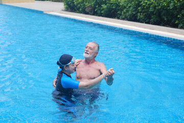 Portrait asia senior woman and caucasian old man dancing together in swimming pool