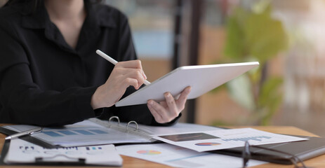 Businesswoman working with a stylus pen on a digital tablet with a laptop computer in a modern...