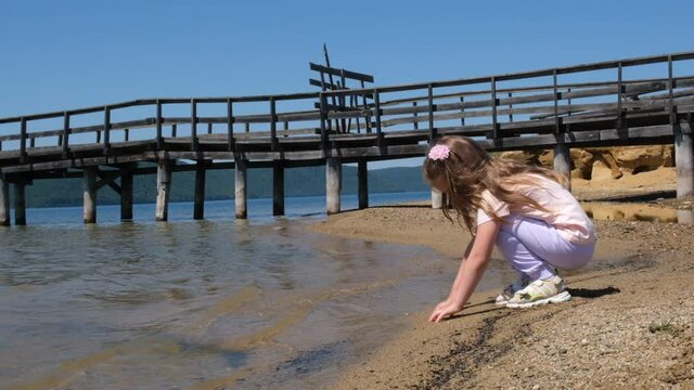 Child playing on beach ,little girl dig wet sand on beach. Leisure games with sea sand . activity kids play