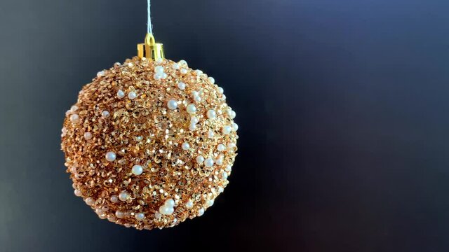 Nice golden glitter Christmas ball moves on black background. Christmas greeting animation with free space for your text