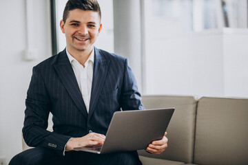 Young handsome business man working on computer on a sofa in office