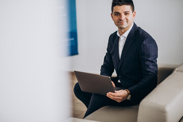 Young handsome business man working on computer on a sofa in office