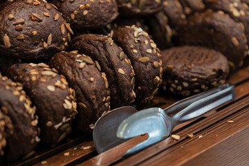 Close-up photo of rye buns with sunflower seeds in wooden trays at the hotel restaurant.