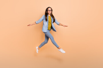 Fototapeta na wymiar Full size photo of positive woman jumping walking in air enjoy free time on weekend isolated on beige color background