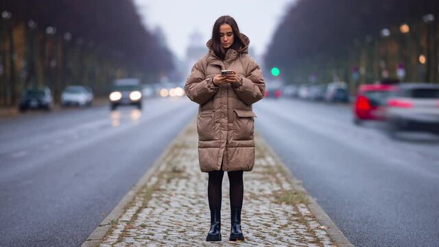 Time lapse of young woman using smart phone surfing social media, checking news, playing mobile games or texting messages staying on public street.