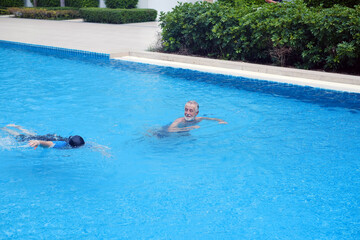 asia senior woman training caucasian old man swimming together