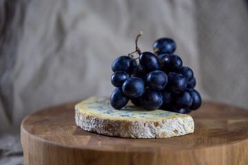 Blue cheese and blue grapes on a wooden plate