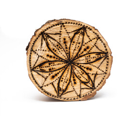 burnt pattern on round cut of a tree isolated on a white background. A flower burned on a tree