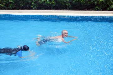 asia senior woman training caucasian old man swimming together