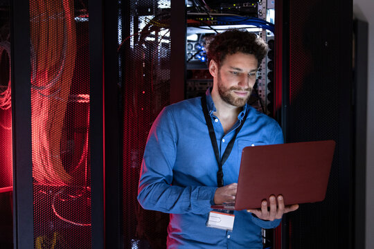 Male engineer working on laptop in server room