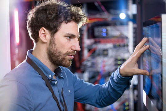 Male IT technician looking at computer screen in data center