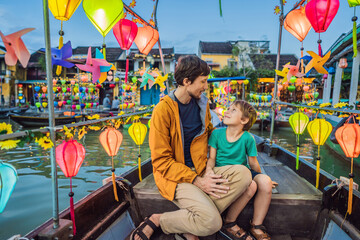 Happy family father and son of travelers ride a national boat on background of Hoi An ancient town,...