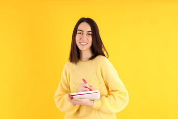 Fototapeta premium Attractive girl with notebook on yellow background