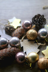 Various wooden Christmas ornaments, golden baubles and pine cones on wooden background. Selective focus.