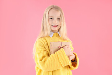 Cute little girl holds gift box on pink background