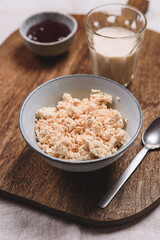 Homemade melted cheese curd served with milk and jam on wooden cutboard. Healthy breakfast. Haze effect. Selective focus
