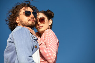 Fashion models couple wearing sunglasses. Sexy woman and handsome young man portrait over light...