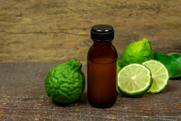 Bergamot oil in bottle and fresh bergamot fruit with green leaf on wooden background.