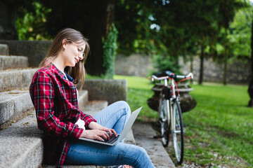 Young woman using laptop in public park