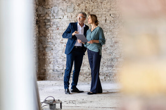 Male and female architects discussing while standing at construction site
