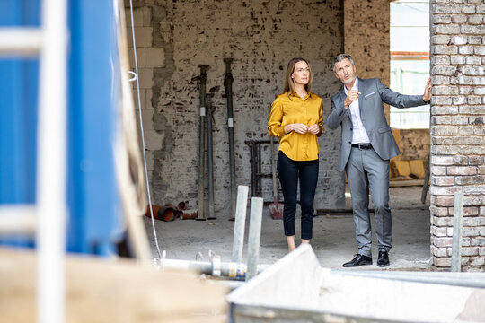 Male client discussing with female architect while standing at construction site
