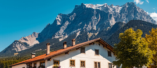 Beautiful alpine summer view with a building and the famous Zugspitze summit in the background at...