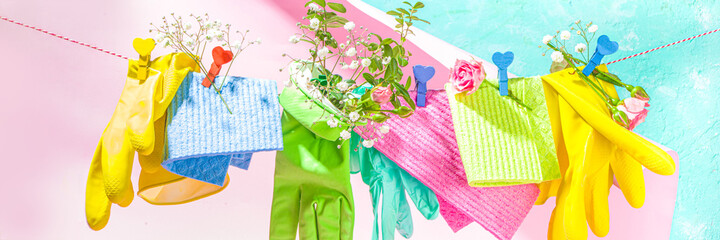 Creative bright spring cleaning concept. Tools, bottles, accessories for cleaning house with spring flowers and leaves hang on clothesline, box, bright sun light copy space - obrazy, fototapety, plakaty