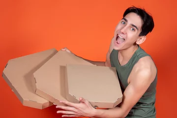 Foto op Plexiglas Joyful man with pizza boxes on an orange background. Delivery courier. © Denis