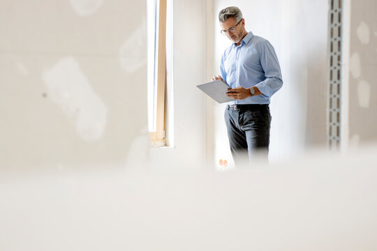 Male professional using digital tablet by wall at site
