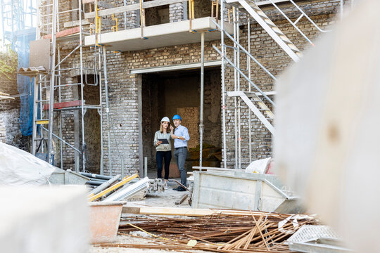 Female client discussing with male architect while standing at construction site