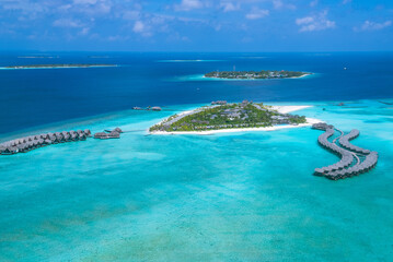 Aerial view of a tropical Maldives island with over the water bungalows villas