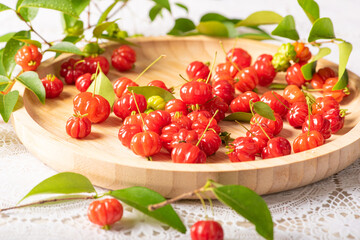 Pitangas placed on a wooden plate on a white plastic tablecloth on the table, selective focus.