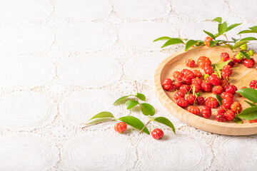 Pitangas placed on a wooden plate on a white plastic tablecloth on the table, selective focus.