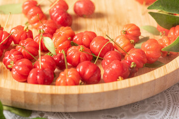 Pitangas placed on a wooden plate on a white plastic tablecloth on the table, selective focus.