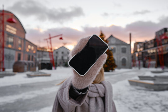 The Girl Shows A Blank Phone Screen On The Street. Close-up Smartphone With Copy Space For Text And Informational Content