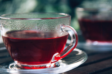 Glass cups of hot red hibiscus tea on a wooden tray at terrace. Close up