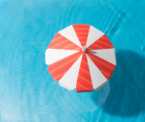 The concept of a tropical beach from a mini toy umbrella from the sun. blue background with shadows...