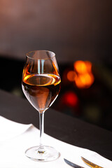 A glass of rose wine photographed on a white table against a modern fireplace. Drink is prepared to be served at dinner.