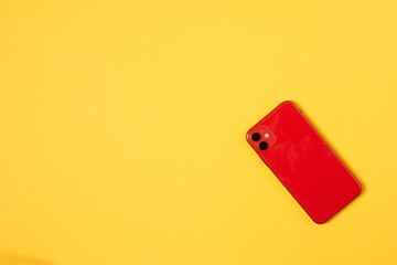 top view red smart phone on yellow background with copy space. red phone on colored background flat lay. concept electronics and gadgets
