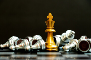 Gold king chess piece win over lying down silver team on black background