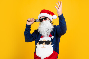 happy bearded man in santa claus hat and knitted sweater with microphone celebrate new year winter...