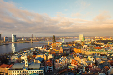 Fototapeta na wymiar Panorama of the city of Riga on a sunny day, blue sky, morning, sunset, a view of the old town, narrow streets, red brick roofs of houses, cathedrals, a river and bridge.