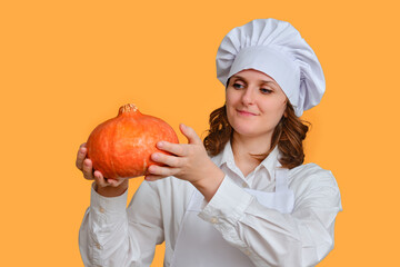 Happy woman chef with big red pumpkin in hands on studio background, copy space